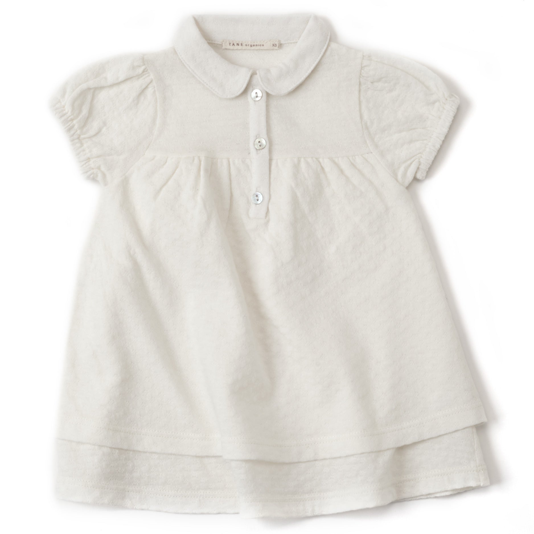 cream color pointelle double layered cap sleeved dress with peter pan collars and 3 natural shell buttons at the center front. Soft elastics at cuffs with delicate shirrings at the sleeves and the bodice. 100% organic cotton pointelle knit.
